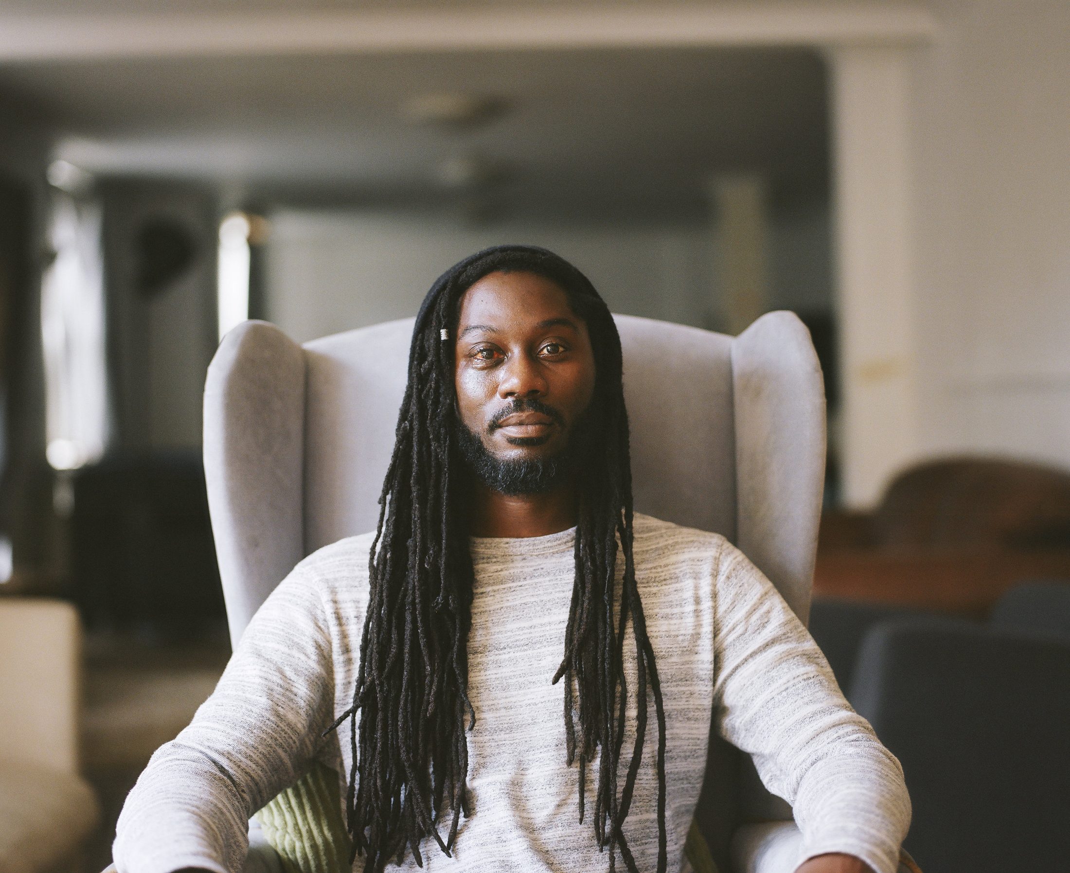 Property guardian with long locs, wing-back chair