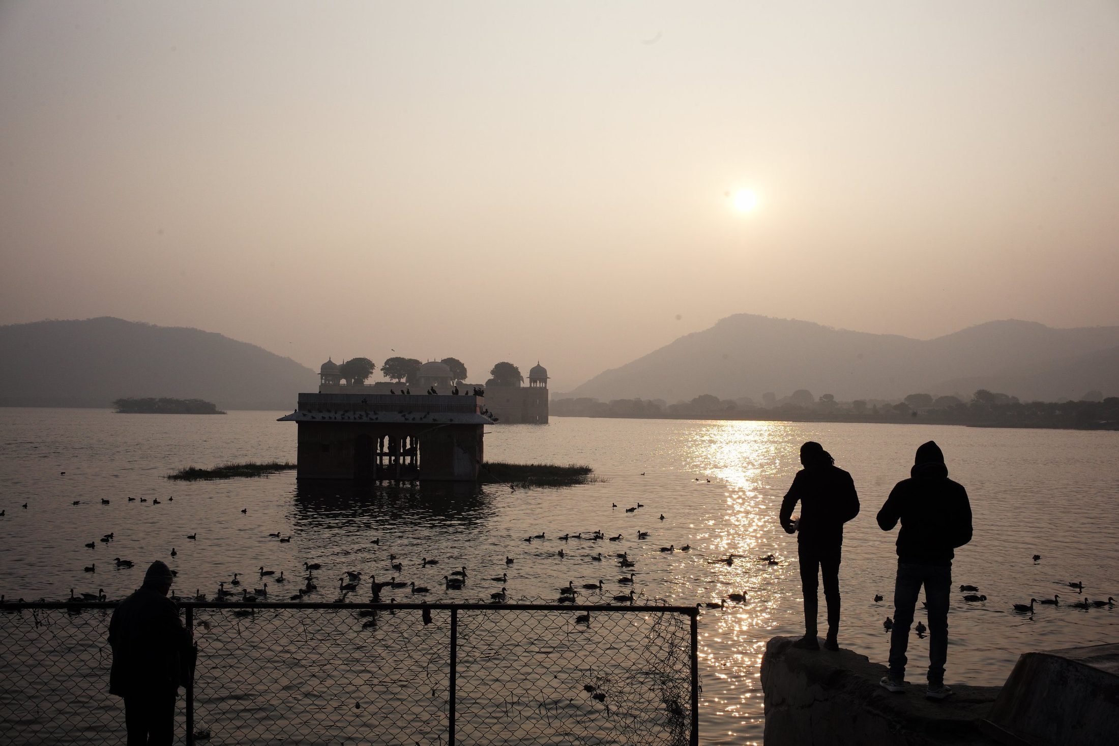 Two figures watching the lake palace at sunset